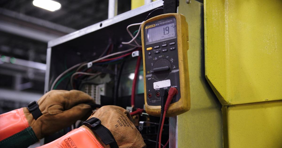 Electrician testing a control panel with a multimeter