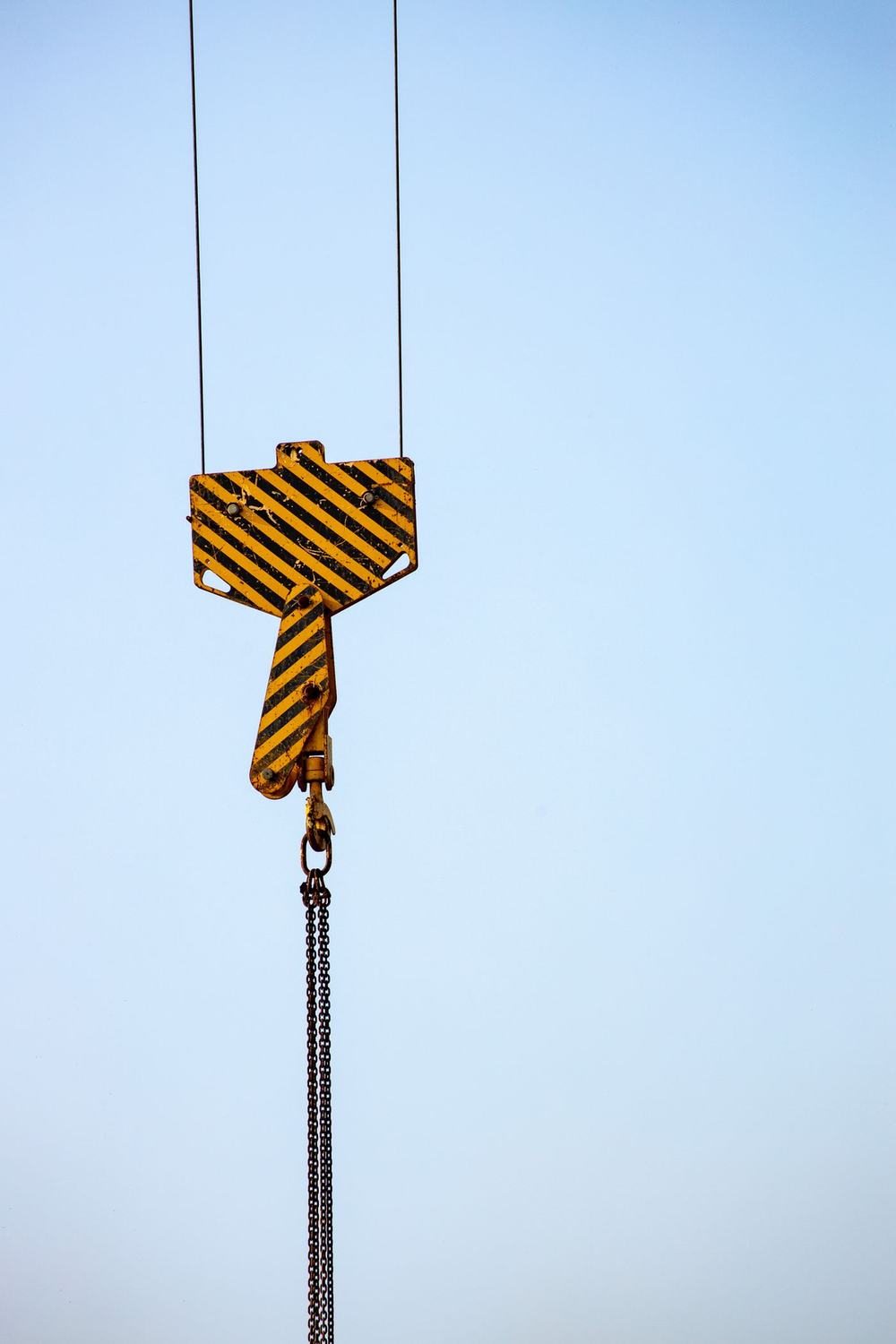 Crane hook block against a clear sky