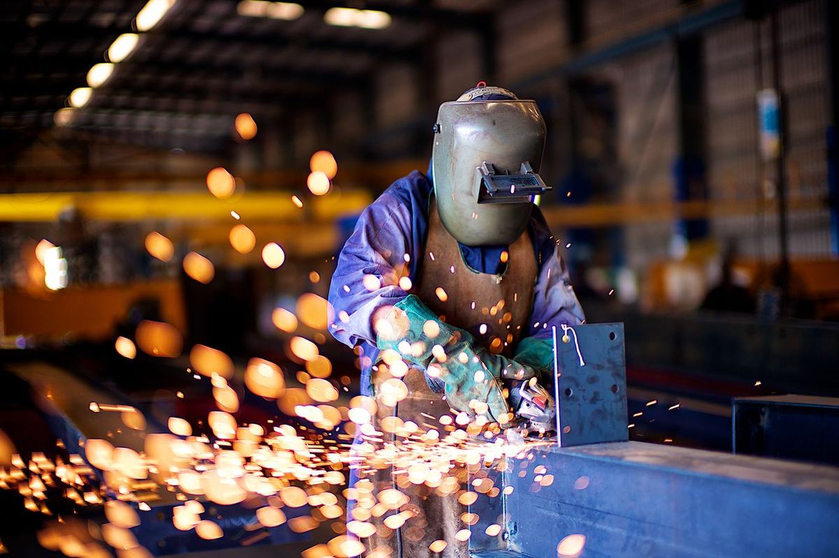 Worker cutting steel with an angle grinder, sparks flying