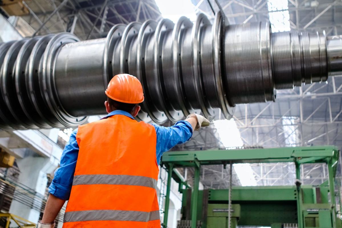 Engineer in a hard hat and hi-vis vest inspecting heavy machinery